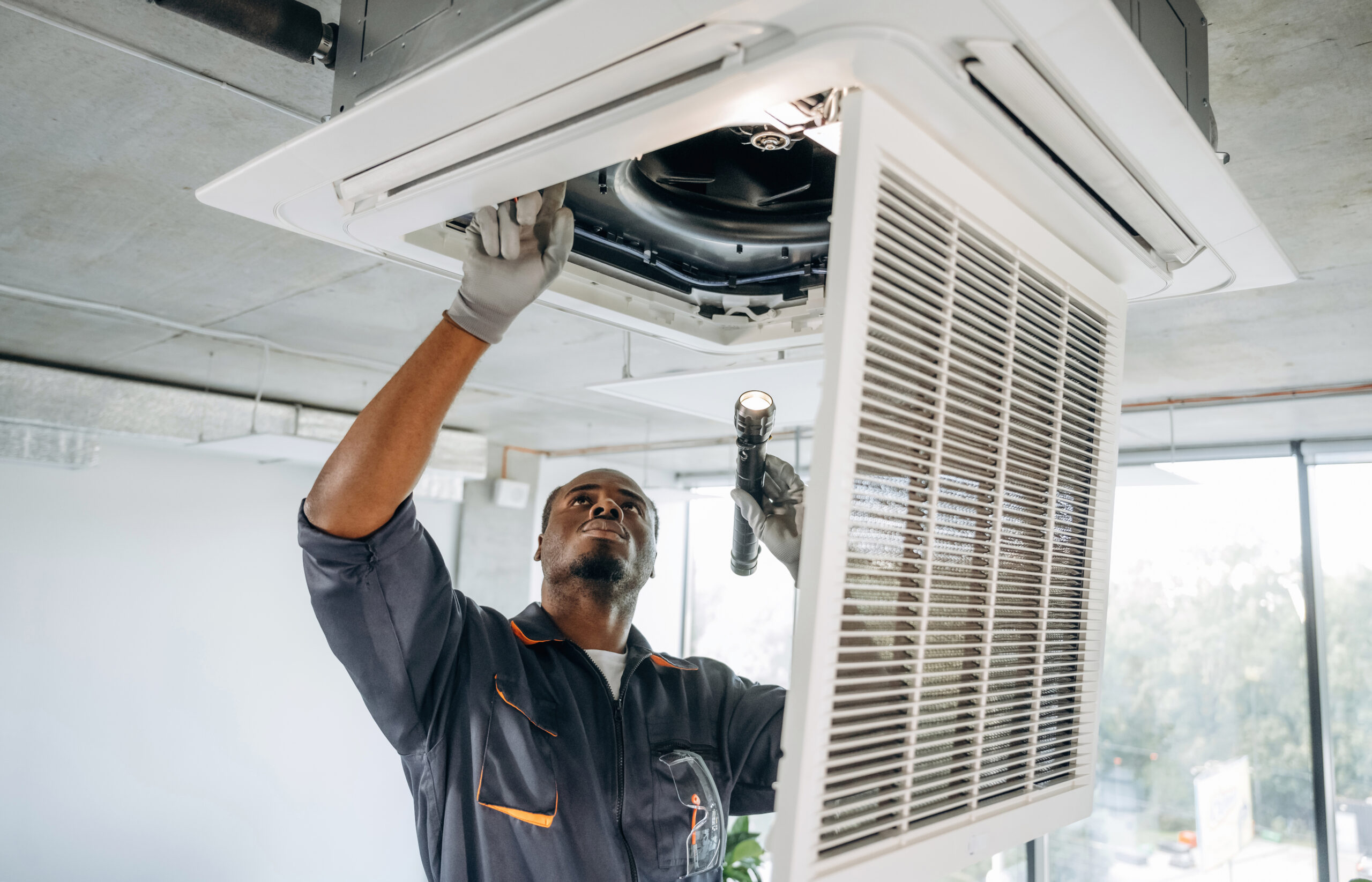 Technician inspecting ceiling air conditioning unit.