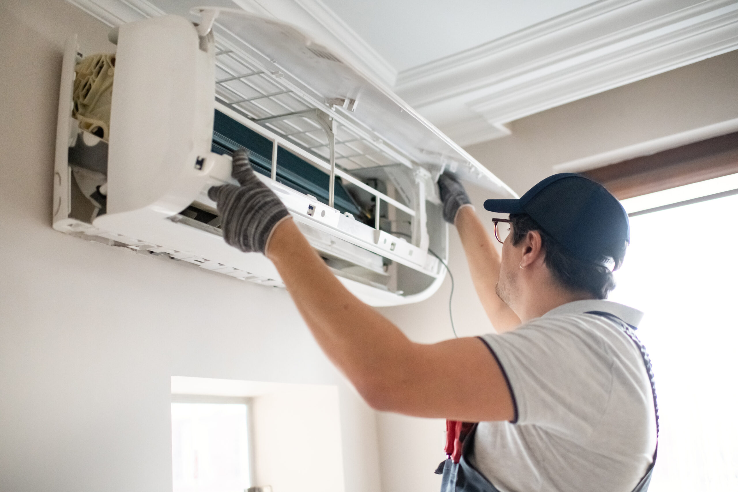 Technician repairing wall-mounted air conditioner.