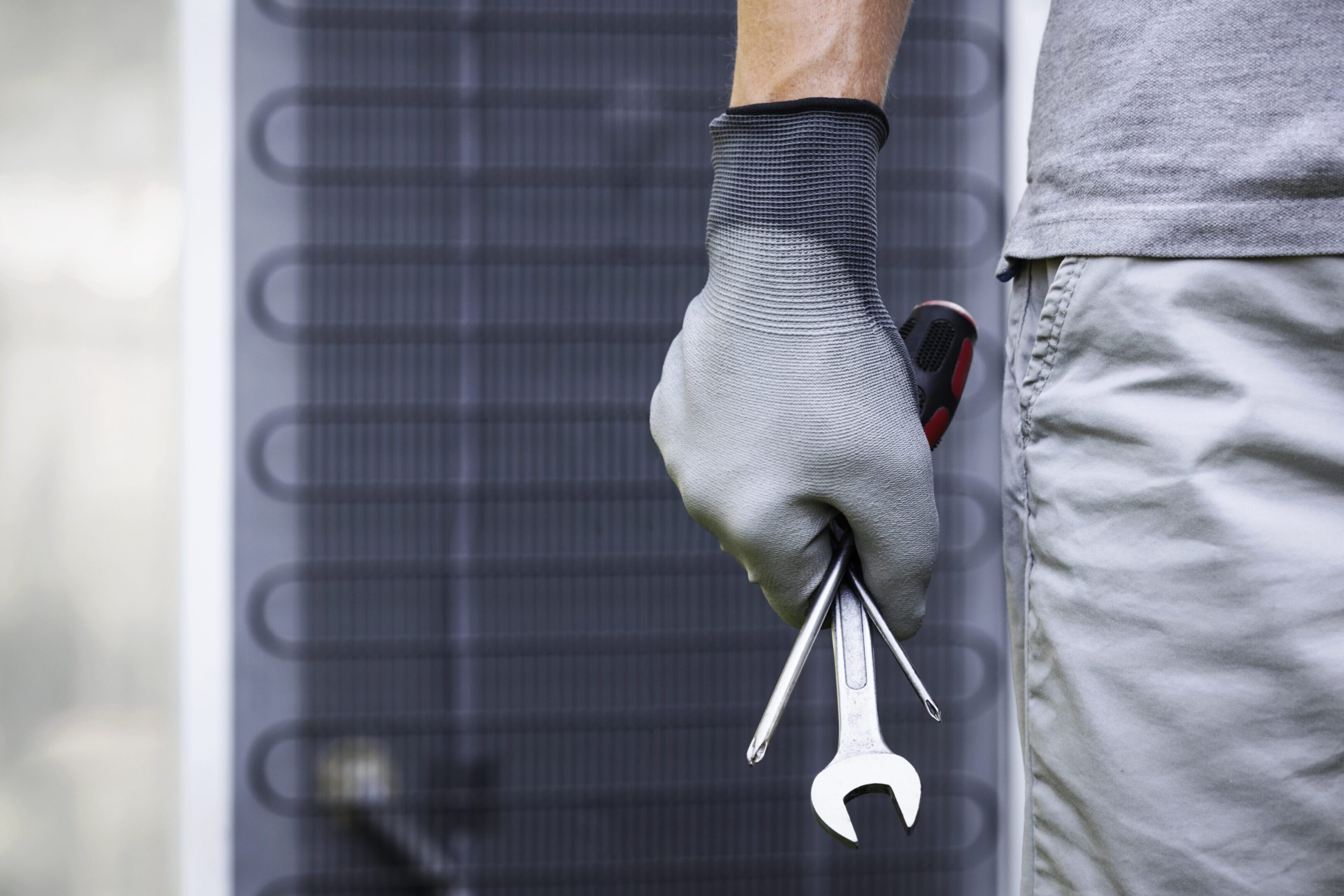 Technician holding tools preparing for air conditioner maintenance.