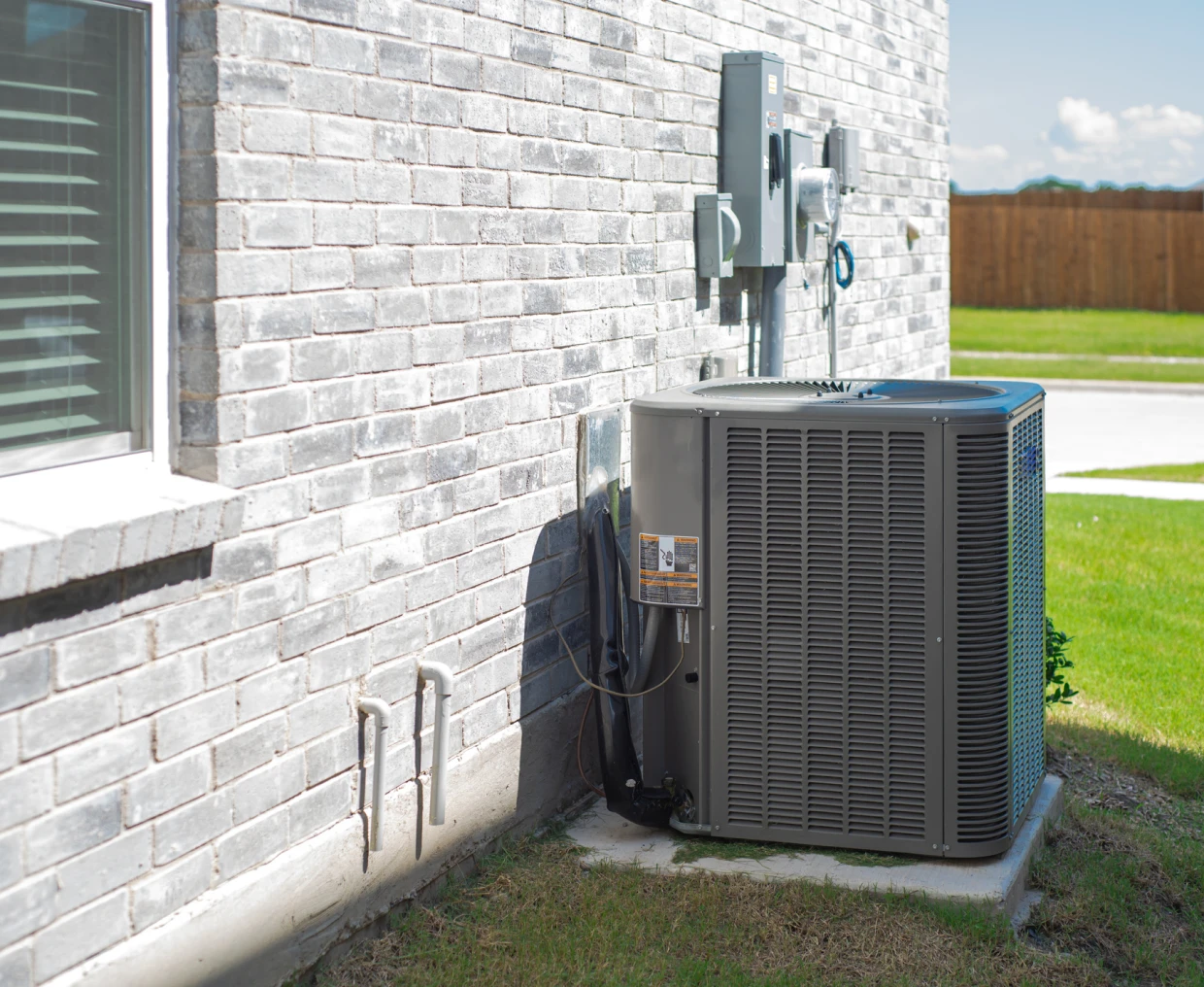 Air conditioning unit outside brick house.